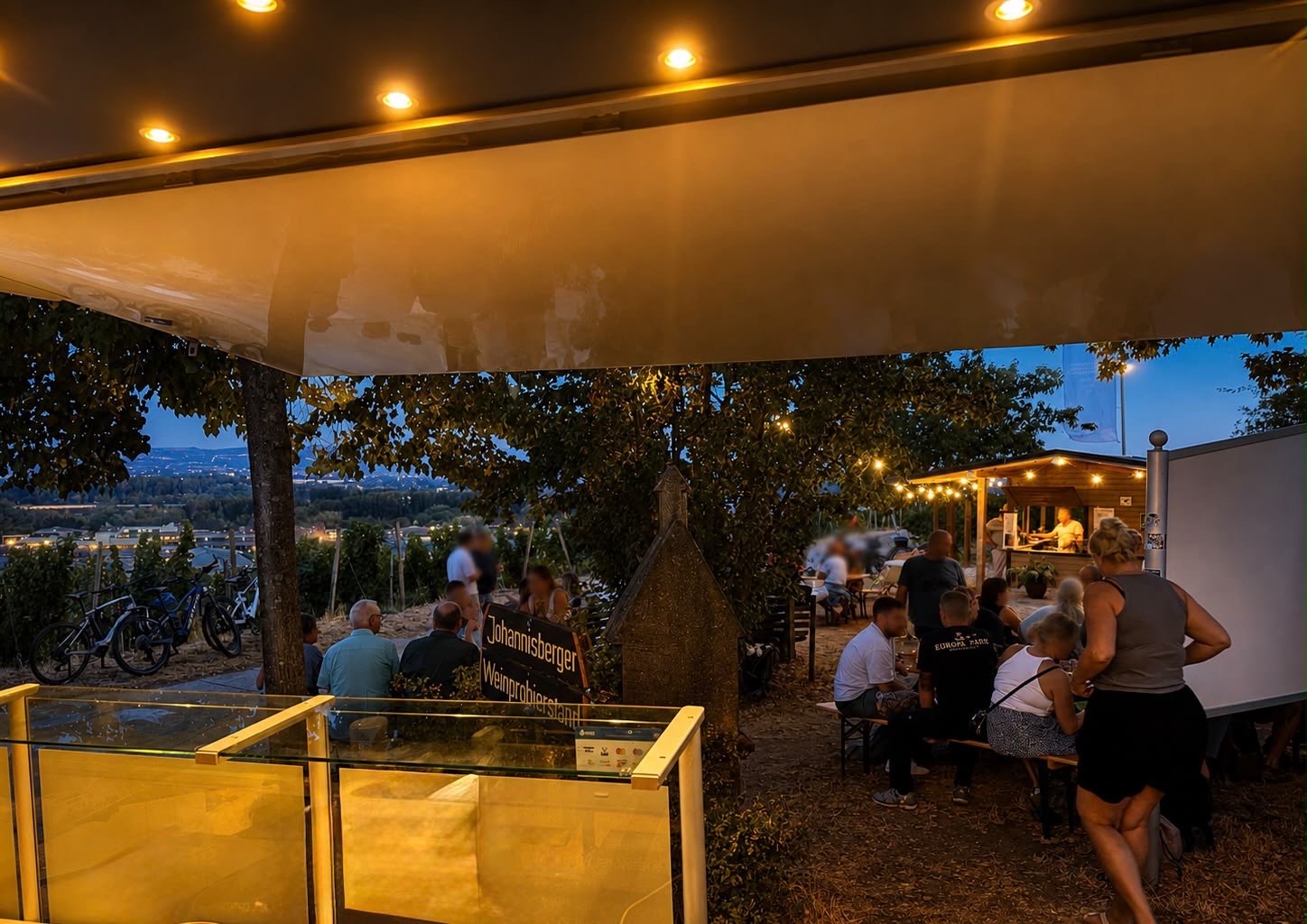 Gäste bei einem abendlichen Weingut-Event mit Blick auf das Rheintal und den SteinertFood Foodtruck.